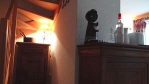 Eine Küchenzeile mit Holdekor, einer Arbeitsplatte, einer Kaffeemaschine und einer Flasche Genepi Dolin.