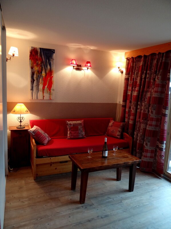 Een gezellige woonkamer met een rode bank, een houten salontafel en een lamp.