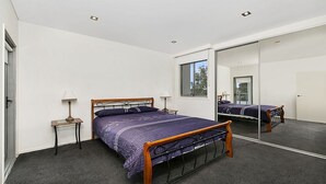 Una camera da letto con un letto grande, un comodino, una lampada e uno specchio.