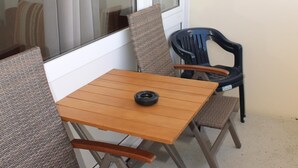 A balcony with a wooden table and two chairs, one with a woven seat and the other with a plastic seat. - Holiday apartment K112 for 2-4 persons near the beach (Schönberg OT Holm)