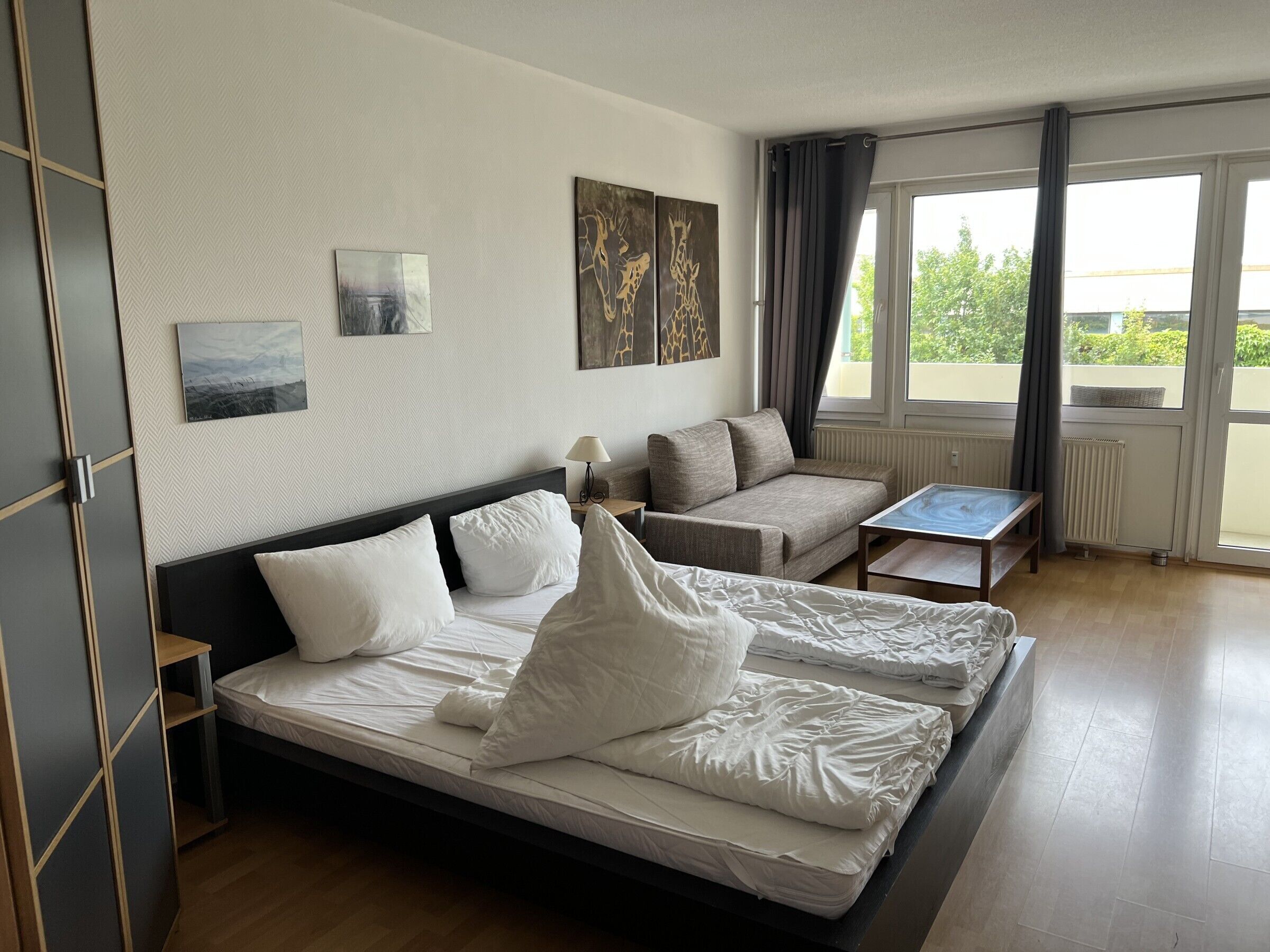 Une chambre d’hôtel avec un lit, un canapé, une petite table et des œuvres d’art accrochées aux murs.
