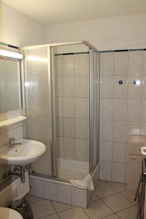 A bathroom with a glass-enclosed shower, a sink, and a mirror. - Holiday apartment K112 for 2-4 persons near the beach (Schönberg OT Holm)