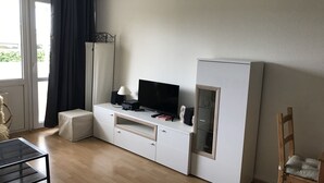 A hotel room with a bed, a desk with a computer and speakers, a TV, a wardrobe, and a chair. - Holiday apartment K112 for 2-4 persons near the beach (Schönberg OT Holm)