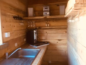 A compact kitchen with wooden walls, a stainless steel sink, a coffee machine, and a shelf with glasses and a small appliance. - VILLA CLIMATISEE WITH PRIVATE SWIMMING POOL (Porto-Vecchio)