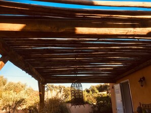 A wooden pergola with a hanging lantern, a door, and a wall-mounted light fixture. - VILLA CLIMATISEE WITH PRIVATE SWIMMING POOL (Porto-Vecchio)