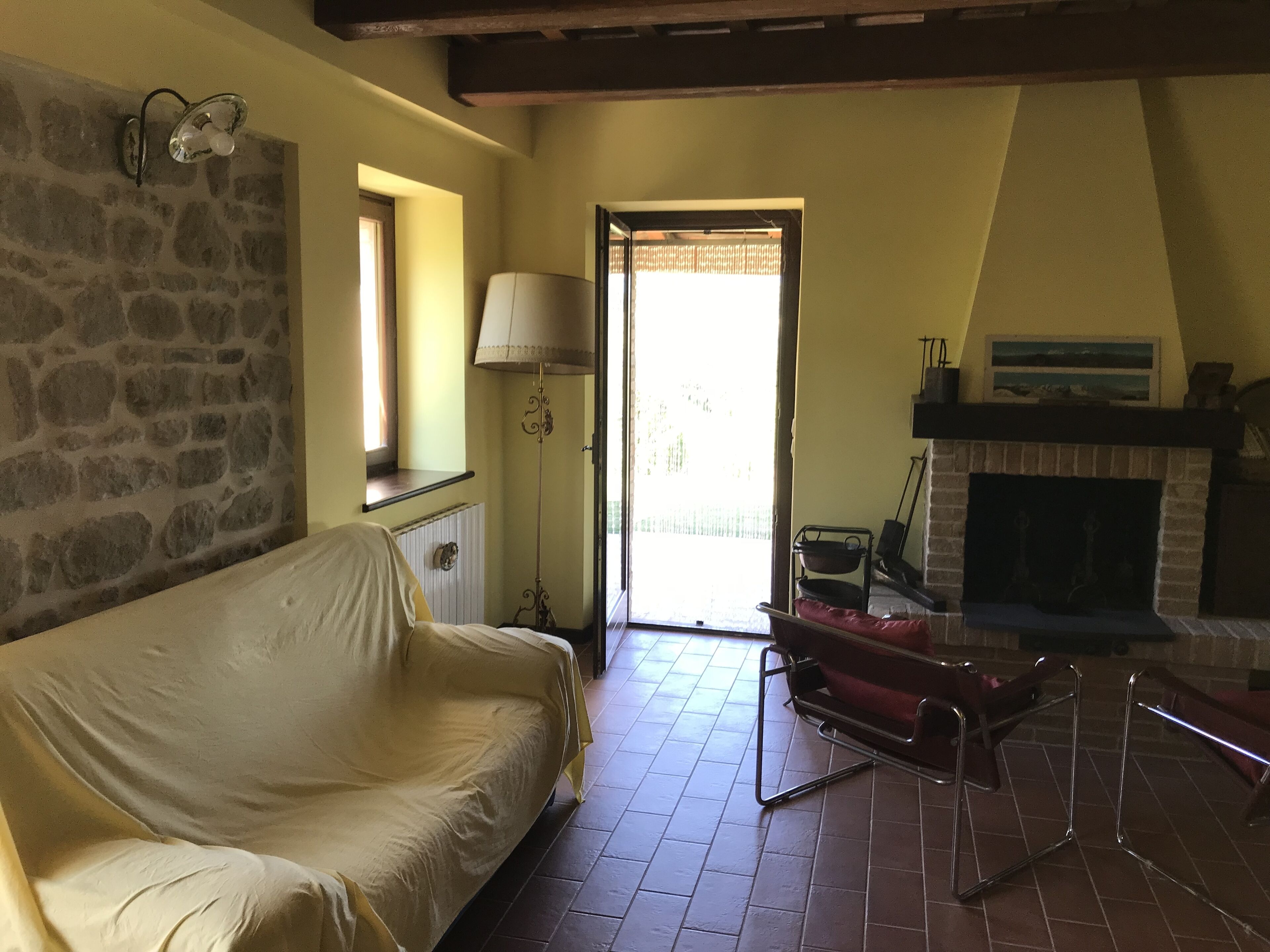 Un salon chaleureux avec un mur en pierre, un canapé, une cheminée et une vue par la fenêtre.