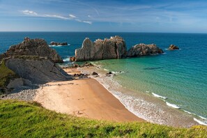 A coastal landscape with a sandy beach, rocky formations, and clear blue waters. - APARTMENT FOR 4 PEOPLE IN LIENCRES (Liencres)
