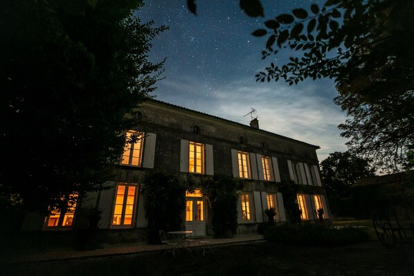 A large, two-story building with multiple windows, some of which are illuminated.