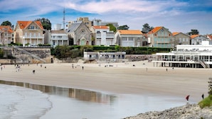 En strand med bygninger i baggrunden, blandt andet en kirke og boliger.