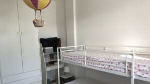 A bunk bed with a floral bedspread, a white wardrobe, and a desk with a lamp and storage boxes. - Alice's house relax and cordiality in the Pontine plain ... (LATINA)