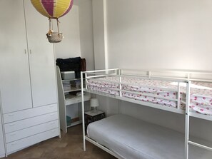 A bunk bed with a floral bedspread, a white wardrobe, and a desk with a lamp and storage boxes. - Alice's house relax and cordiality in the Pontine plain ... (LATINA)