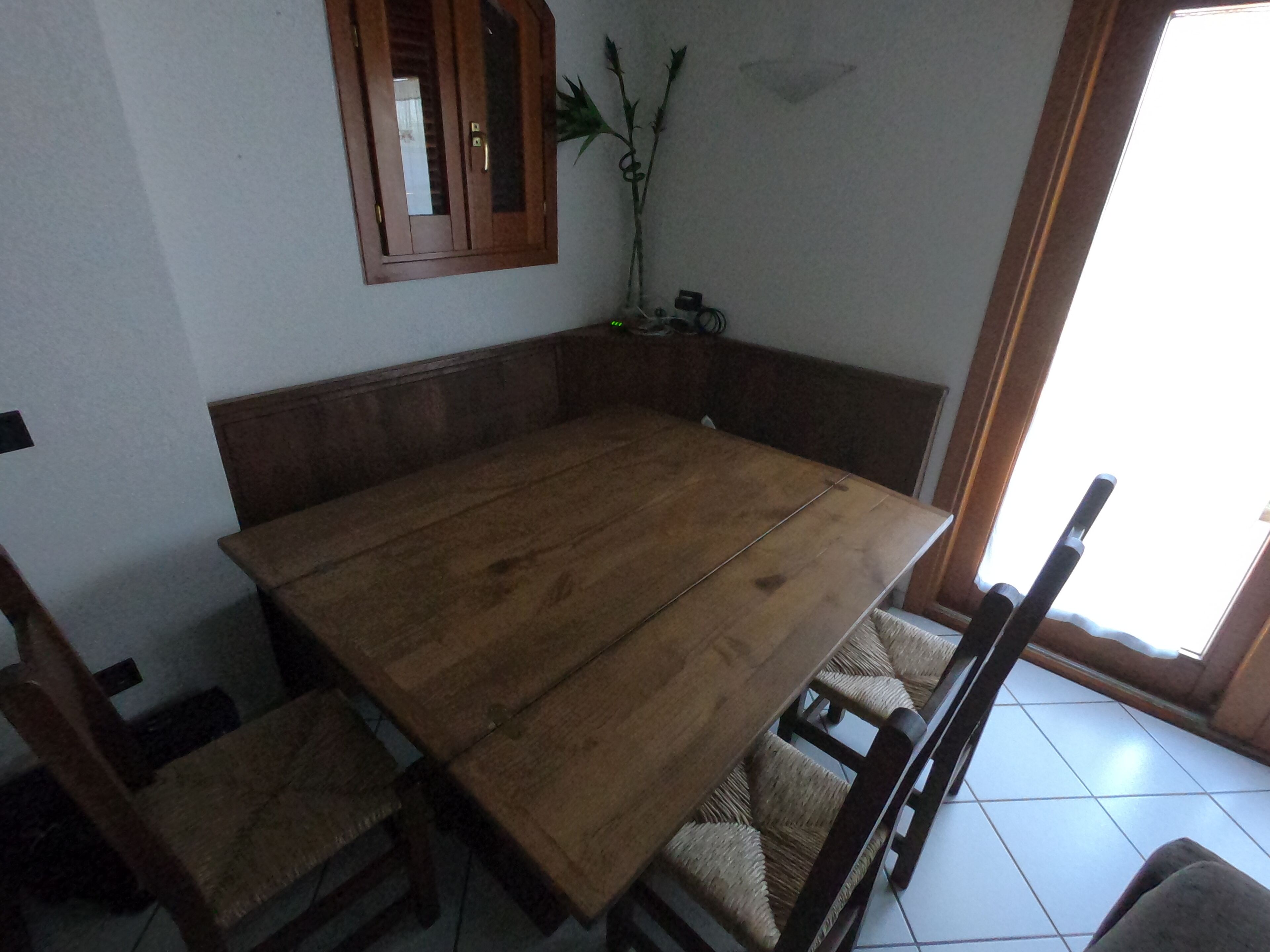 Un coin repas avec une table et des chaises en bois, un buffet en bois et une plante en pot.