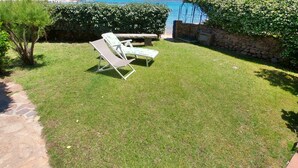 A grassy outdoor area with two lounge chairs and a stone wall. - Maison "The Little Gate", seaside paradise. (porto san paolo)