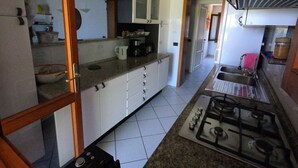 A kitchen with white cabinets, a gas stove, a coffee maker, and a sink. - Maison "The Little Gate", seaside paradise. (porto san paolo)