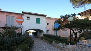 A stone pathway leading to a building with a pink facade and green shutters. There are signs indicating no entry for vehicles and a pedestrian zone. - Maison "The Little Gate", seaside paradise. (porto san paolo)