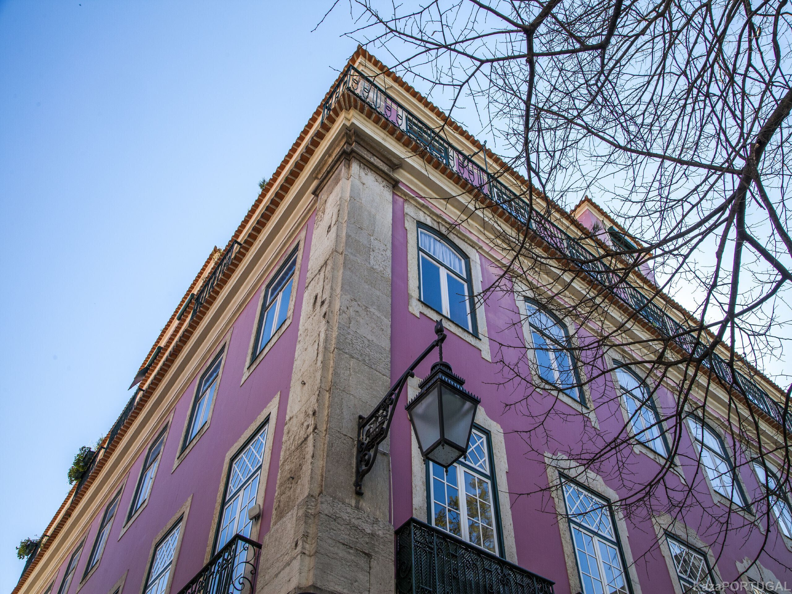 Un immeuble à plusieurs étages, doté d’une façade violette, de grandes fenêtres et d’un lampadaire bien visible.