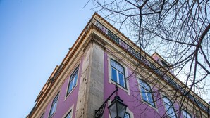 Monikerroksinen rakennus, jonka julkisivu on violetti, siinä on suuret ikkunat ja kadulla näkyvä valaisinpylväs.