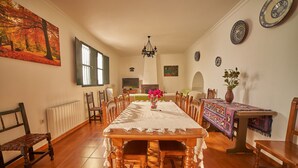 Un comedor con una larga mesa de madera, sillas, una araña y un cuadro en la pared.
