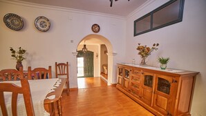 Un comedor con una mesa y sillas de madera, un mueble con puertas de vidrio y platos decorativos en la pared.