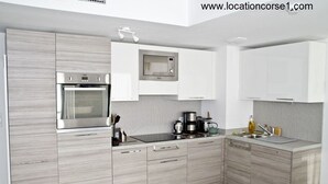 Cozinha moderna com forno embutido, micro-ondas e máquina de café.