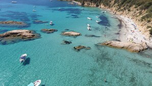 A coastal area with clear turquoise waters, rocky outcrops, and a sandy beach with people and boats. - 2-bedroom apartment on beach, sea and marina view, air-conditioned & WiFi Fiber. (Propriano)