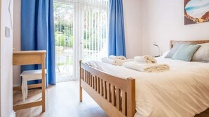 A bedroom with a wooden bed, a bedside table, a chair, and a window with curtains.