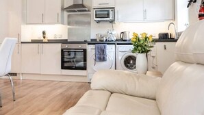 A modern kitchen with a dining area, including a table with chairs, a sofa, and a washing machine.