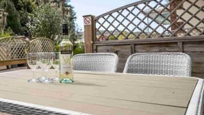 An outdoor patio with a table set for two, featuring a bottle of wine and two glasses.