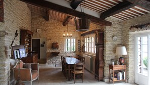 A rustic dining room with a wooden table and chairs, stone walls, and a hanging light fixture. - Stone house in Luberon, heated infinity pool, patio, near Gordes (Murs)