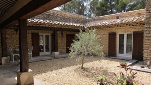 A courtyard with stone walls, wooden beams, and potted plants. - Stone house in Luberon, heated infinity pool, patio, near Gordes (Murs)