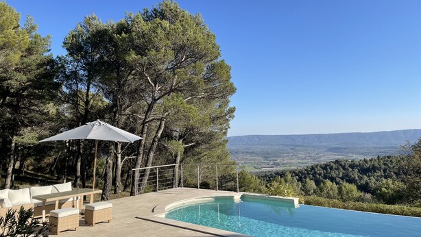 A poolside area with a view of the countryside, outdoor furniture, and a pergola with an umbrella. - Stone house in Luberon, heated infinity pool, patio, near Gordes (Murs)
