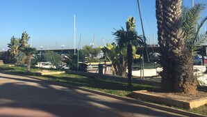 Una calle bordeada de palmeras, cielo azul despejado y un puente a lo lejos.