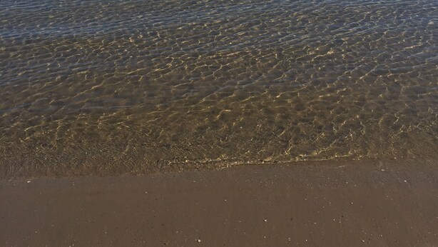 Una masa de agua tranquila con un horizonte despejado y tierras lejanas.