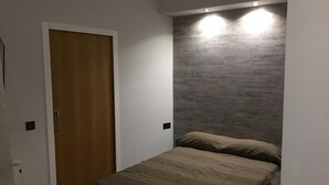 Un dormitorio con cama, una puerta de madera y una pared con textura.