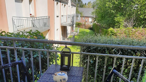 Een balkon met een tafel, twee stoelen, een lantaarn en een theepot.