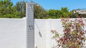 Un área de ducha exterior moderna con un panel vertical y un cabezal de ducha.