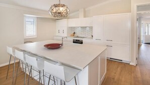 Una cocina moderna con una isla central, armarios blancos y una lámpara colgante de diseño geométrico.