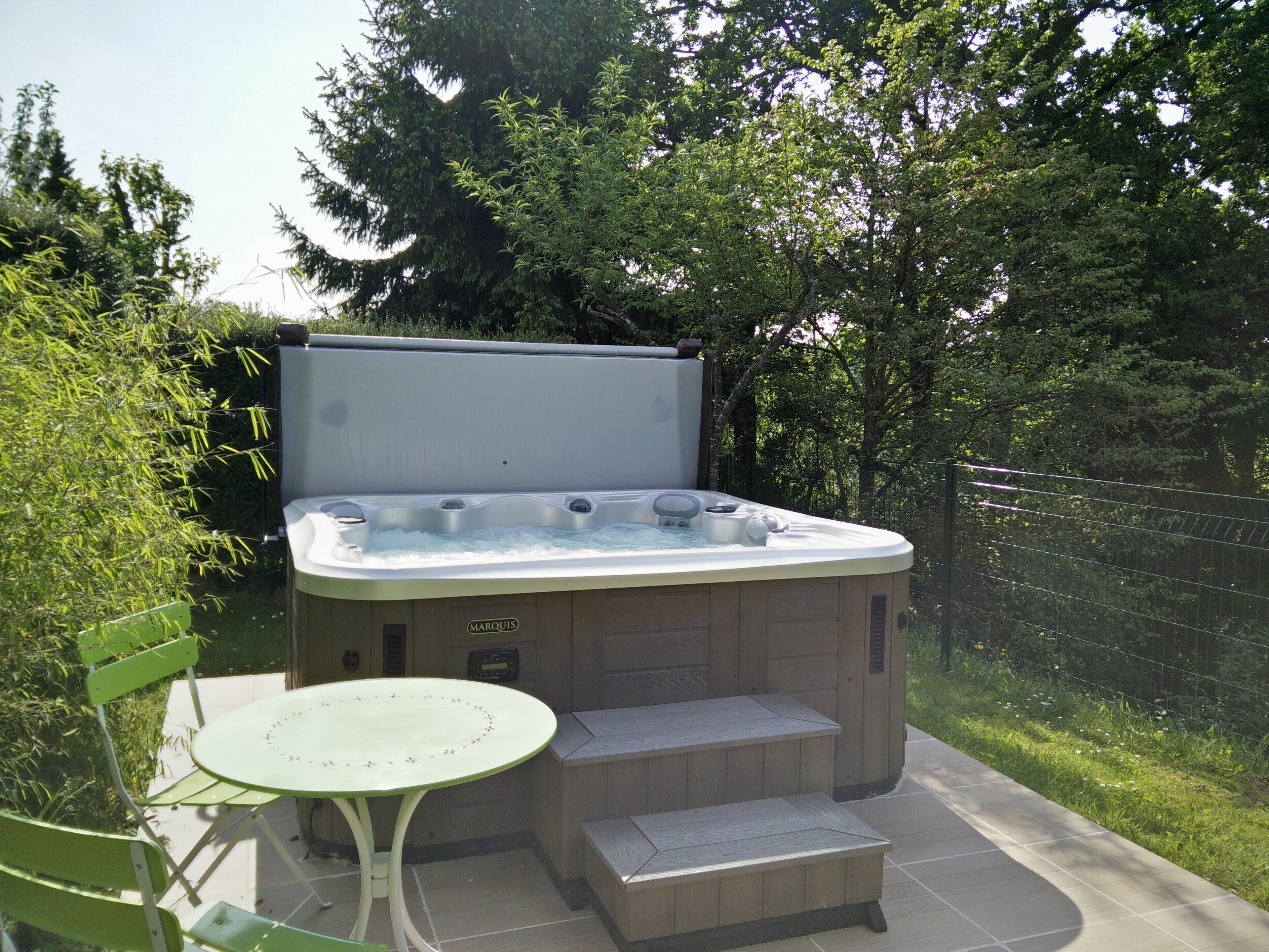 Un bain à remous avec une table et des chaises, installé dans un jardin.