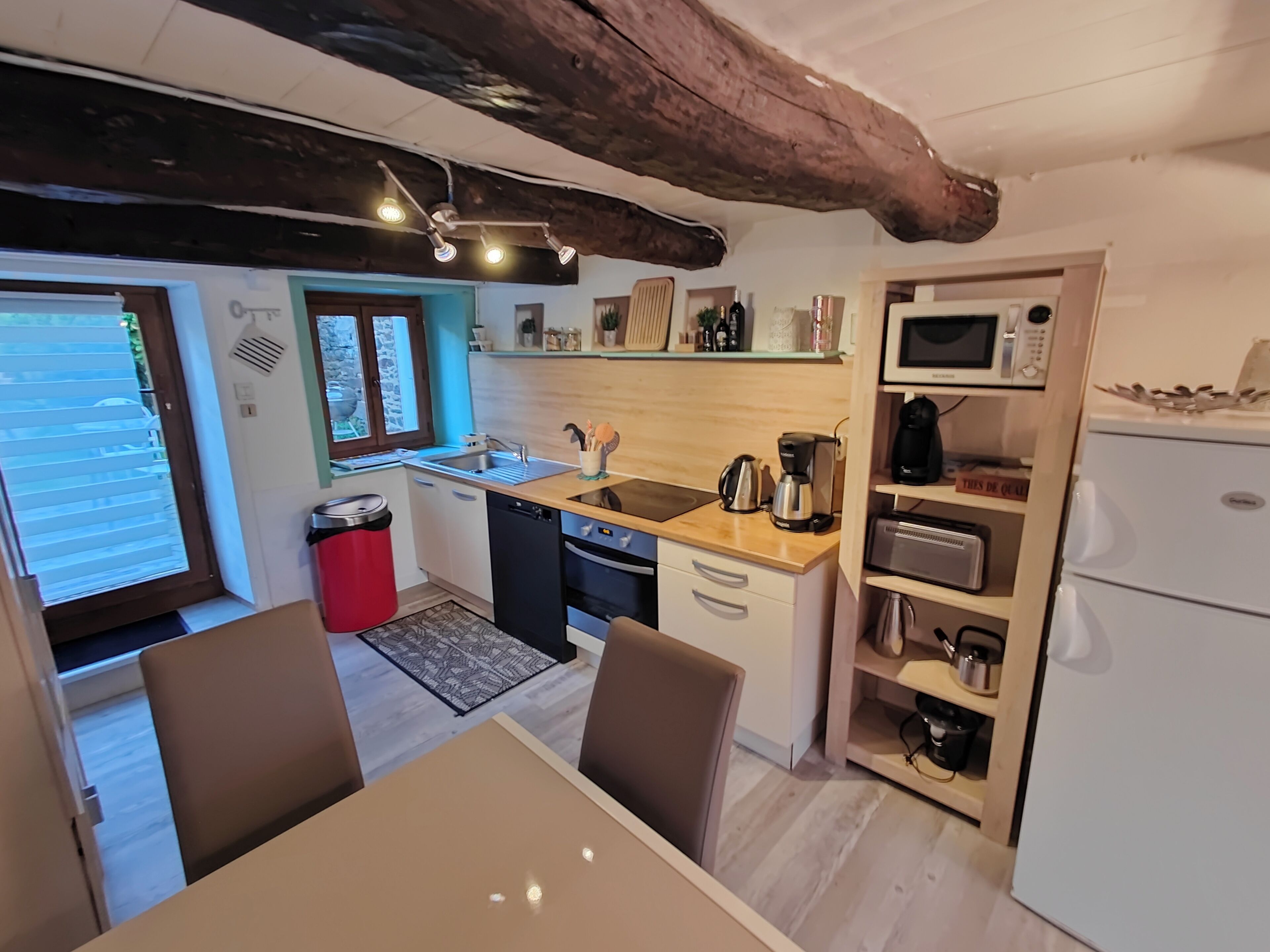 Une cuisine compacte équipée d’un évier, d’une cuisinière et d’un four à micro-ondes. Un coin repas avec une table et des chaises est également disponible.