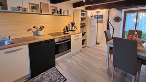 Eine kompakte Küche mit Geschirrspüler, Backofen, Mikrowelle und einer kleinen Essecke mit Stuhl und Tisch.
