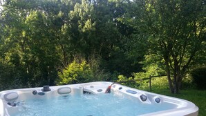 Ein Whirlpool in einem Garten mit einer Holterrasse und einem Holenzaun.