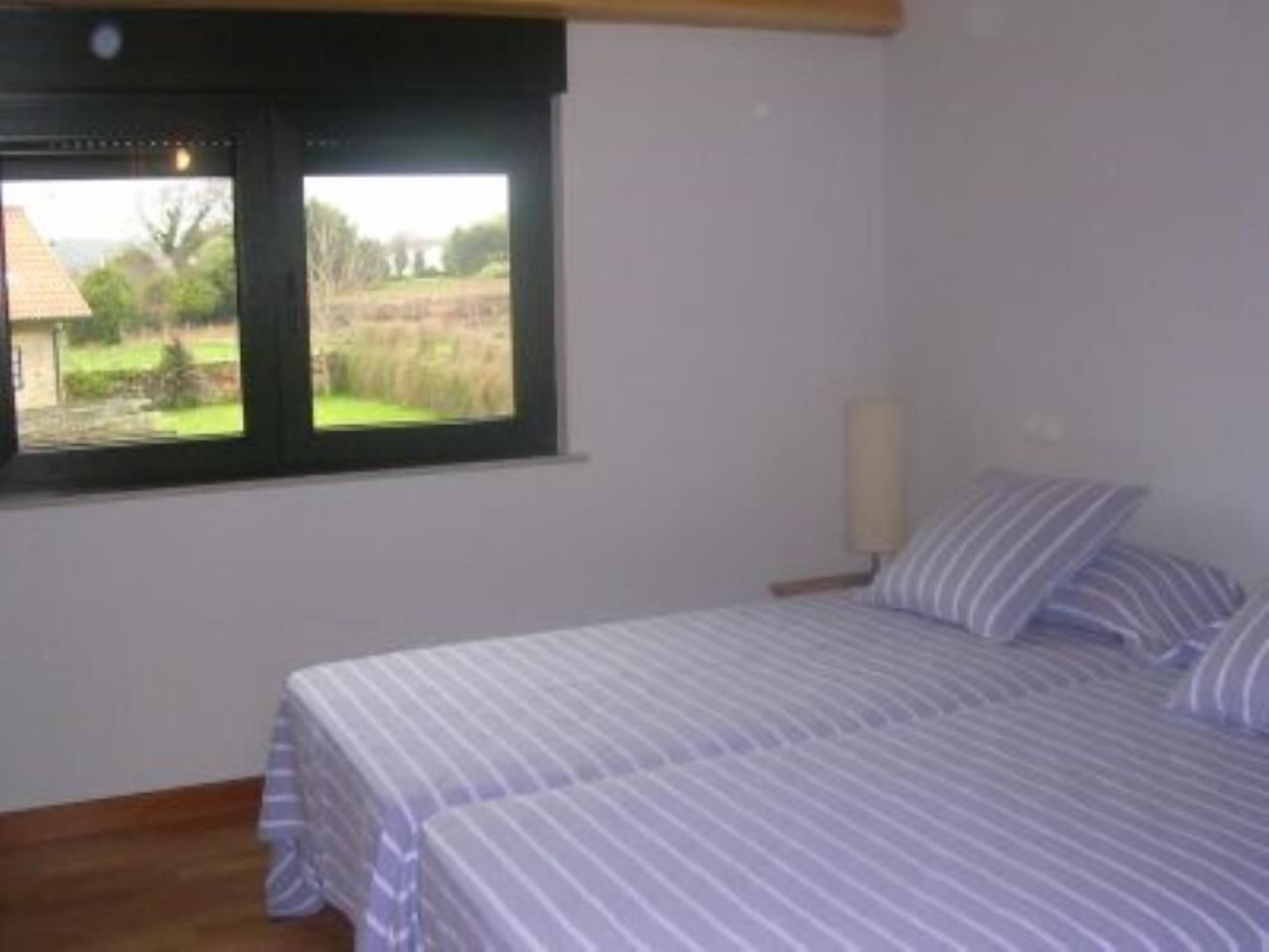 Un dormitorio con dos camas, una ventana que ofrece vistas a un paisaje rural y una lámpara de noche.
