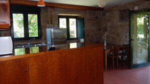 Une cuisine avec un îlot central en bois, des murs en pierre et un réfrigérateur.