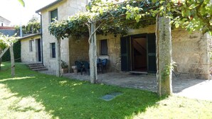 Un bâtiment en pierre doté d’un patio couvert, d’un espace extérieur aménagé pour s’asseoir et d’une pelouse.