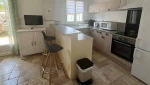 Una cocina moderna con una isla central, taburetes de bar, un microondas, estufa y un cubo de basura.