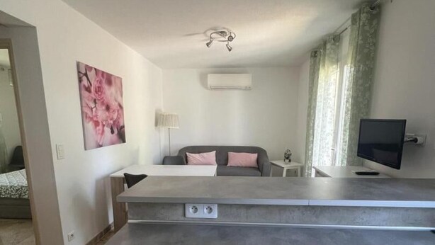 Una sala moderna con un sofá gris, un televisor de pantalla plana y una zona de comedor.