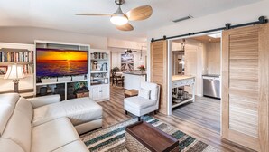 A modern living room with a sofa, a coffee table, a TV, and a bookshelf.