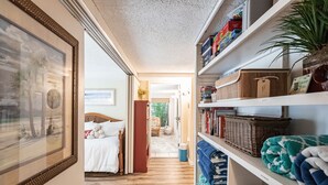 A hallway with a bed, a bookshelf, and a framed picture.