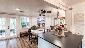 A spacious kitchen with a large island, wooden flooring, and a ceiling fan.