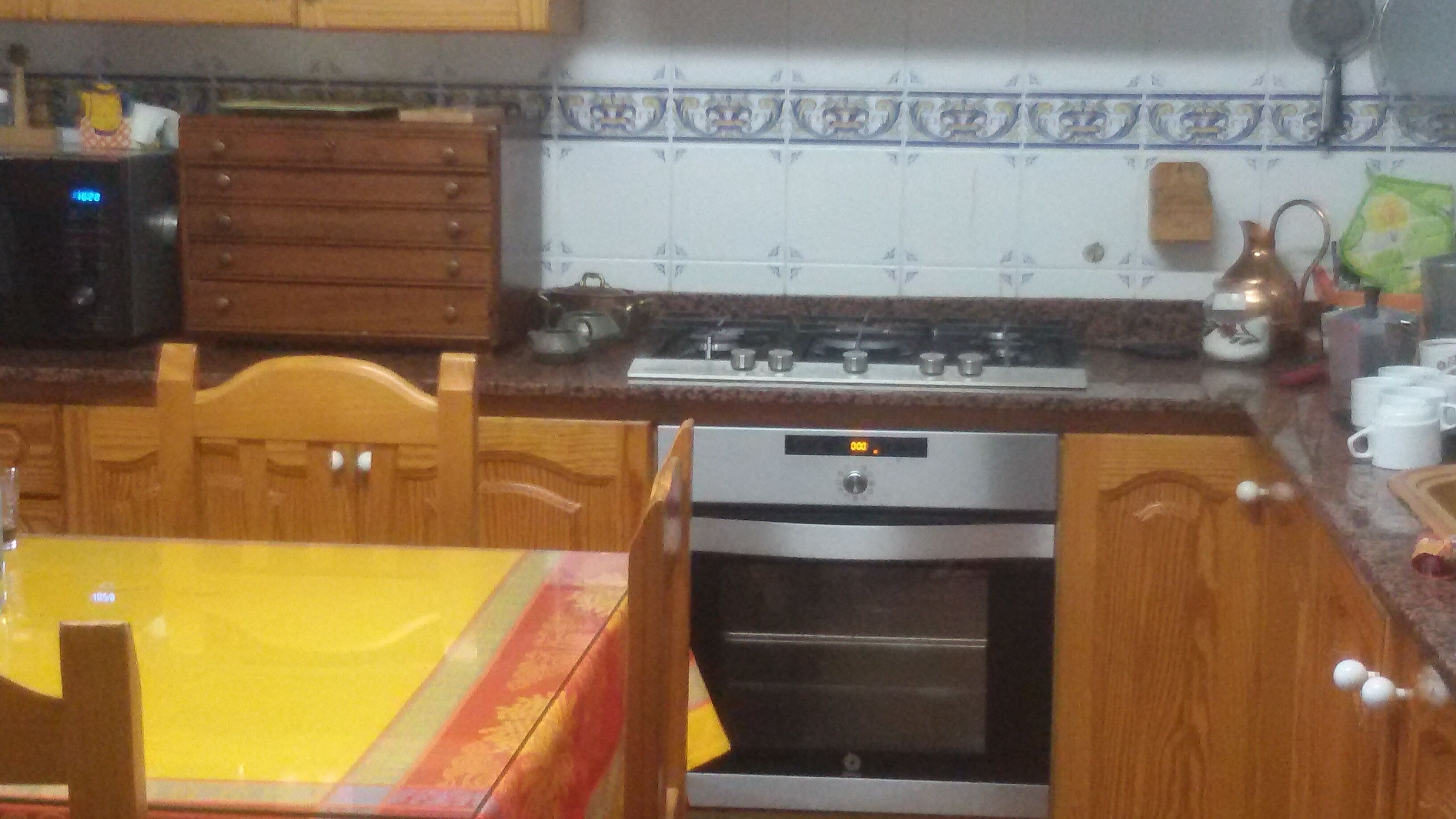 Une cuisine avec des meubles de rangement en bois, une cuisinière et un four.